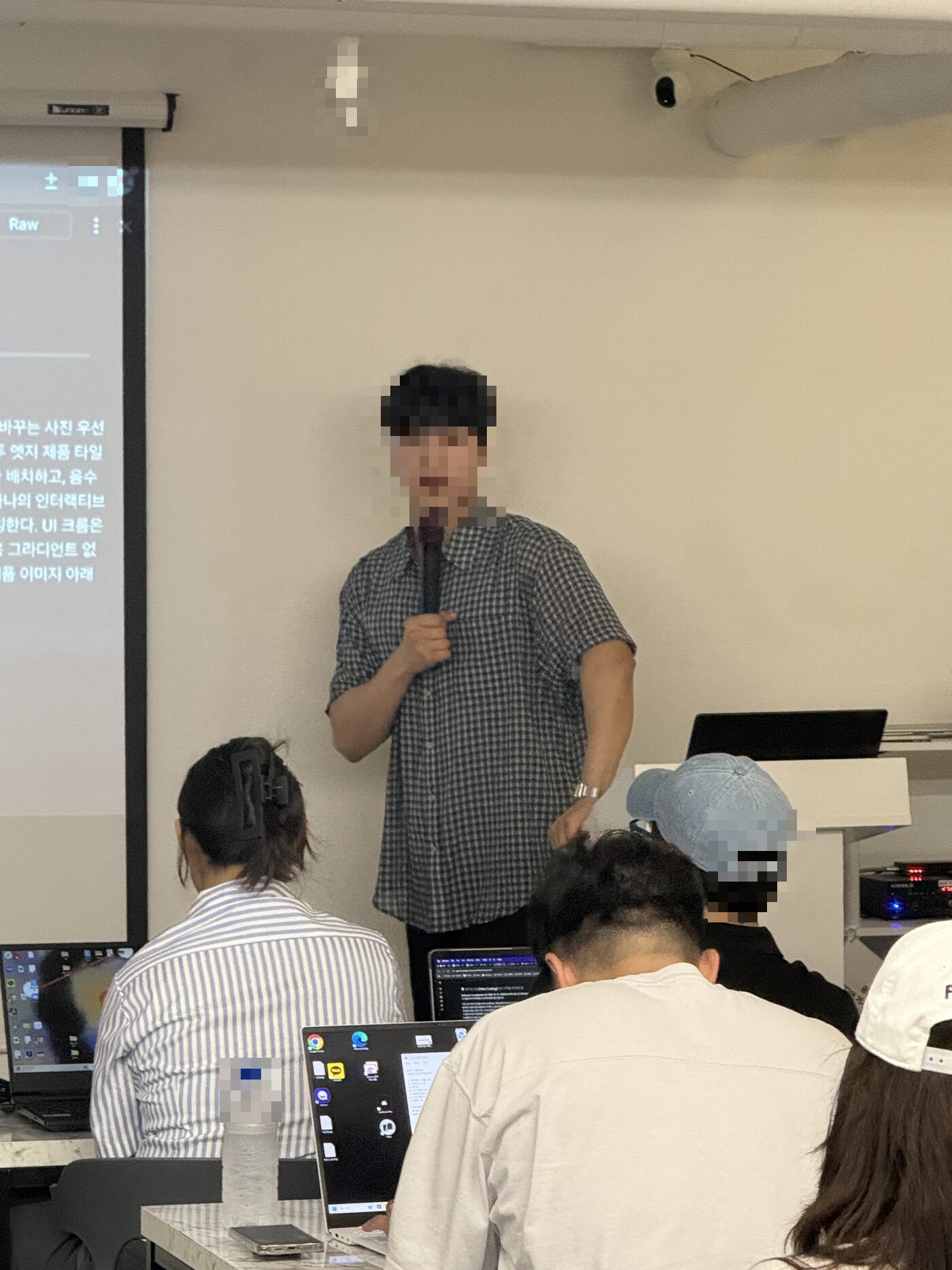 강사가 마이크로 직접 설명하고 수강생들이 가까이서 함께 보는 모습